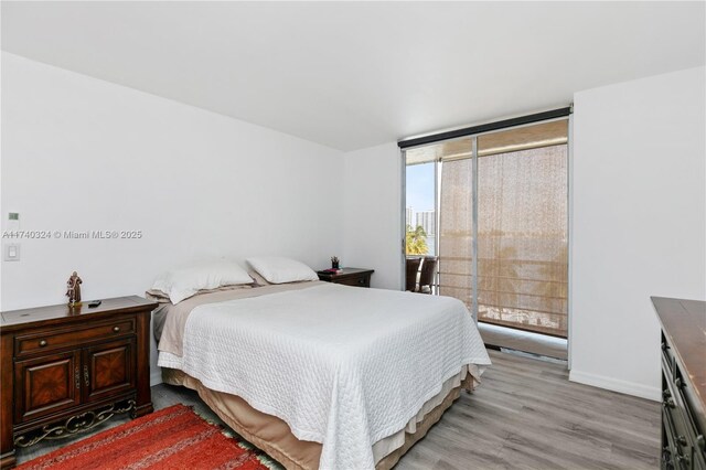 bedroom featuring expansive windows and light hardwood / wood-style flooring