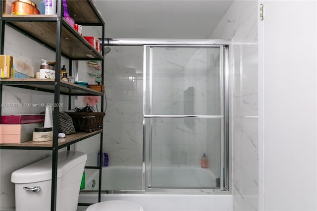 bathroom featuring toilet and combined bath / shower with glass door