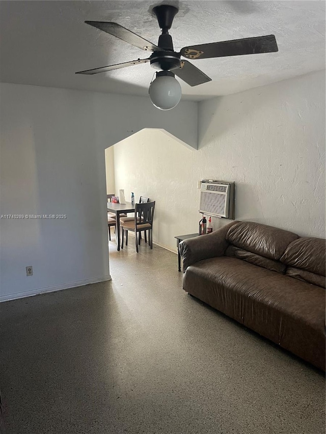 living room with ceiling fan, a textured ceiling, and a wall unit AC