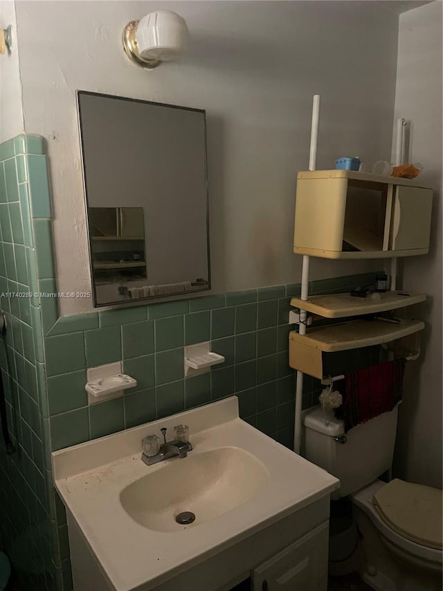 bathroom featuring vanity, tile walls, and toilet