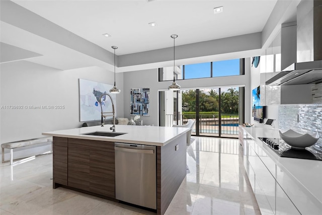 kitchen with pendant lighting, sink, an island with sink, stainless steel dishwasher, and wall chimney exhaust hood