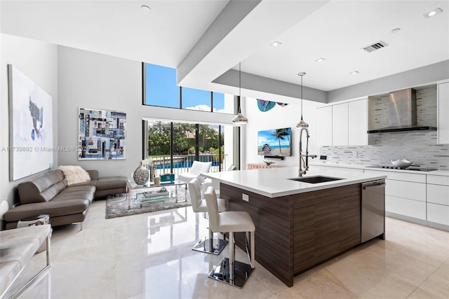 kitchen featuring white cabinetry, dishwasher, an island with sink, and hanging light fixtures