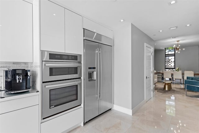 kitchen with stainless steel appliances, a chandelier, and white cabinets