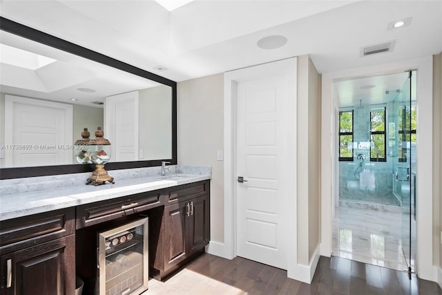 bathroom featuring wine cooler, walk in shower, wood-type flooring, a skylight, and vanity