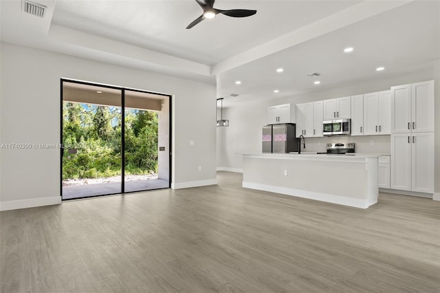 unfurnished living room featuring sink, ceiling fan, and light hardwood / wood-style flooring