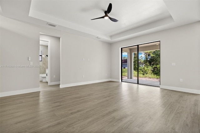 spare room with hardwood / wood-style floors, a tray ceiling, and ceiling fan