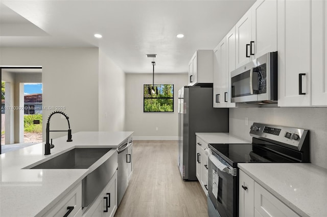 kitchen featuring light stone counters, decorative light fixtures, stainless steel appliances, and white cabinets