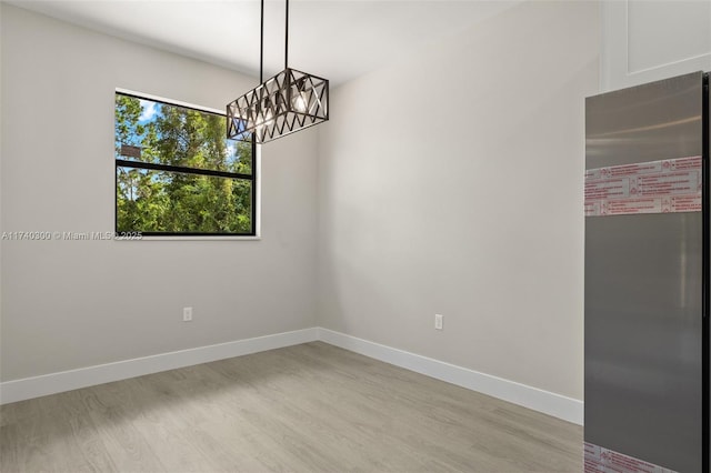 empty room featuring a chandelier and light wood-type flooring