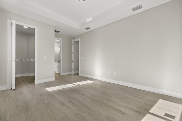 unfurnished bedroom featuring a walk in closet and light hardwood / wood-style flooring