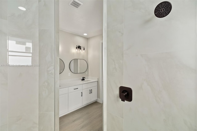 bathroom featuring vanity, hardwood / wood-style flooring, and tiled shower