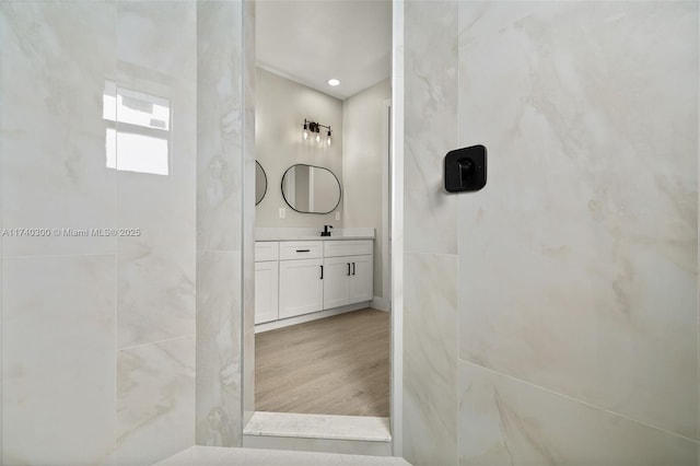 bathroom featuring vanity, hardwood / wood-style floors, and a tile shower