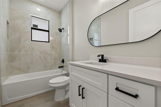 full bathroom with tiled shower / bath combo, vanity, hardwood / wood-style flooring, and toilet