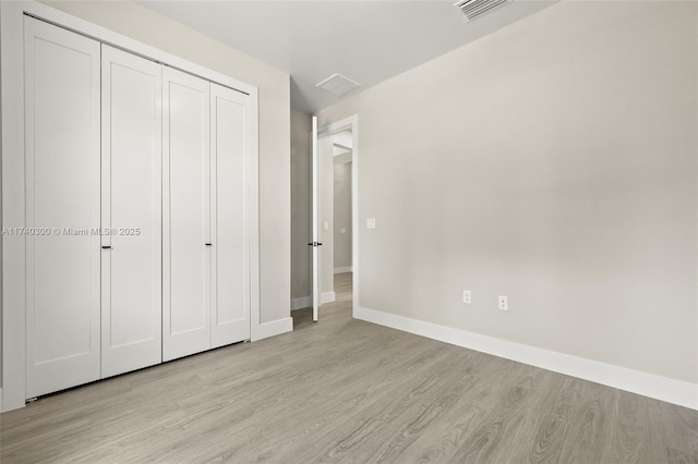 unfurnished bedroom featuring light hardwood / wood-style flooring and a closet