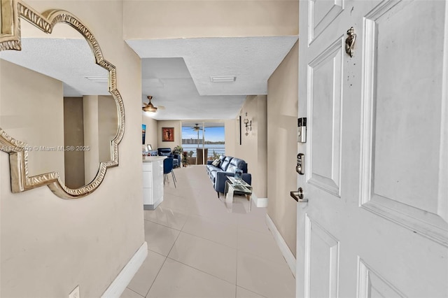 tiled entryway with ceiling fan and a textured ceiling