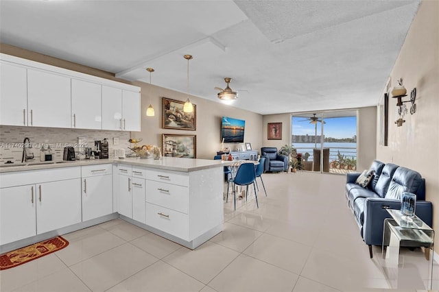 kitchen with sink, white cabinets, hanging light fixtures, ceiling fan, and kitchen peninsula