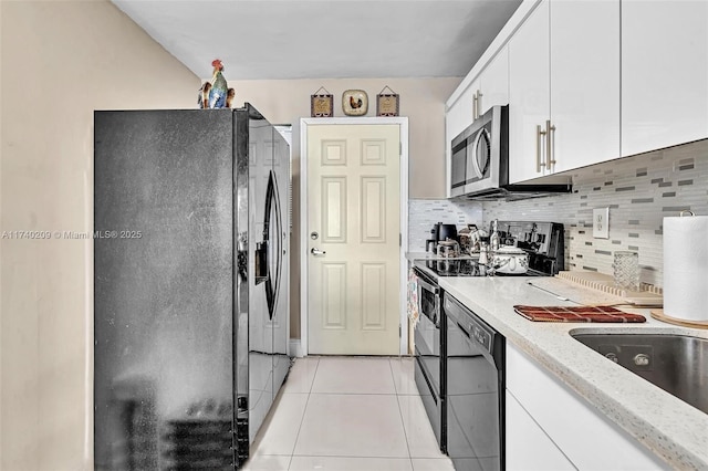 kitchen featuring black appliances, light tile patterned floors, light stone countertops, decorative backsplash, and white cabinets