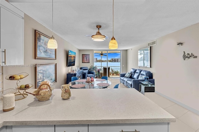 kitchen featuring floor to ceiling windows, a textured ceiling, light tile patterned floors, hanging light fixtures, and white cabinets