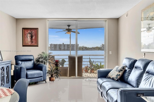 living room featuring a water view, a textured ceiling, and ceiling fan