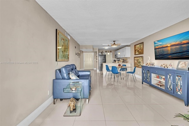 living room featuring ceiling fan, a textured ceiling, and light tile patterned flooring