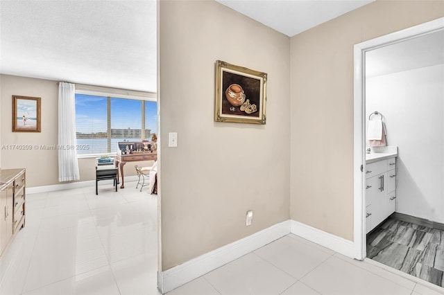 hallway featuring a water view, a textured ceiling, and light tile patterned floors