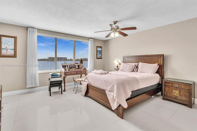 bedroom featuring ceiling fan, light tile patterned floors, a textured ceiling, and a water view