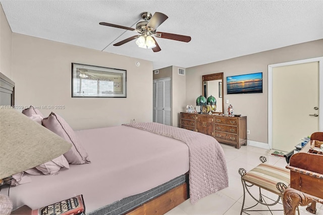 bedroom featuring ceiling fan, a closet, a textured ceiling, and light tile patterned floors