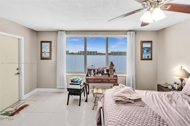 bedroom featuring light tile patterned floors, ceiling fan, a textured ceiling, and a water view