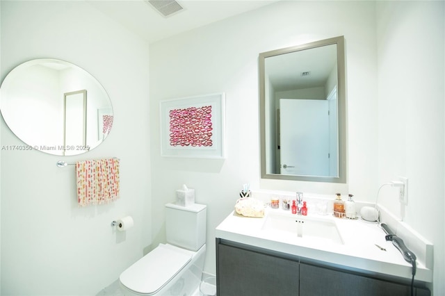 half bathroom featuring visible vents, toilet, and vanity