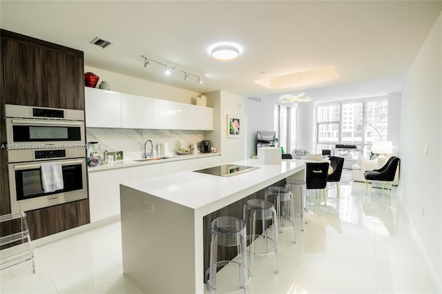 kitchen with visible vents, a breakfast bar, modern cabinets, black electric cooktop, and a sink