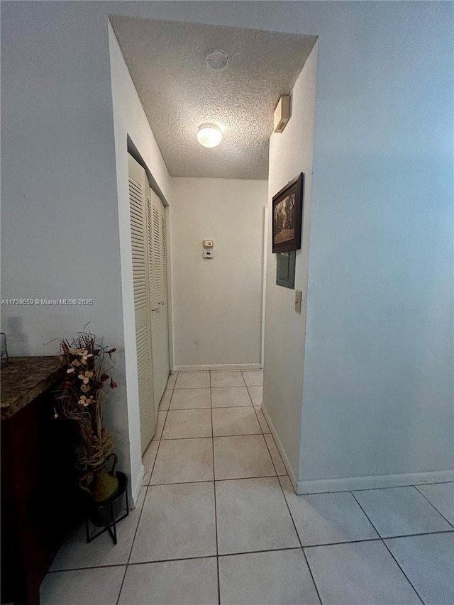 hall with light tile patterned flooring and a textured ceiling