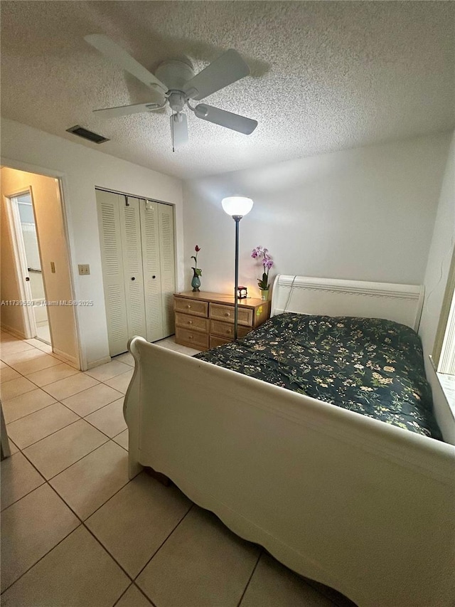 bedroom featuring light tile patterned floors, a textured ceiling, ceiling fan, and a closet