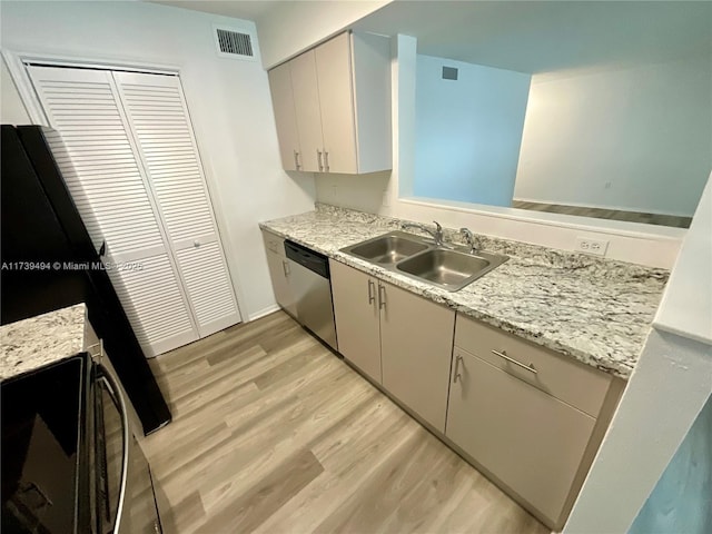 kitchen with sink, white cabinetry, light hardwood / wood-style flooring, stainless steel dishwasher, and light stone countertops