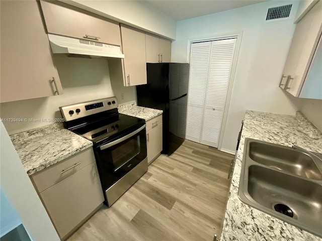 kitchen with black fridge, sink, stainless steel electric range, and light hardwood / wood-style flooring