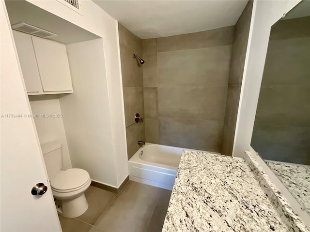 bathroom featuring tiled shower / bath, tile patterned floors, and toilet