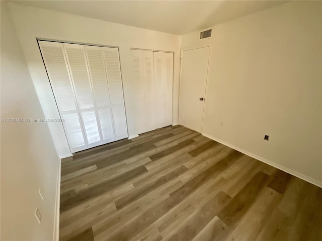 unfurnished bedroom featuring multiple closets and dark wood-type flooring