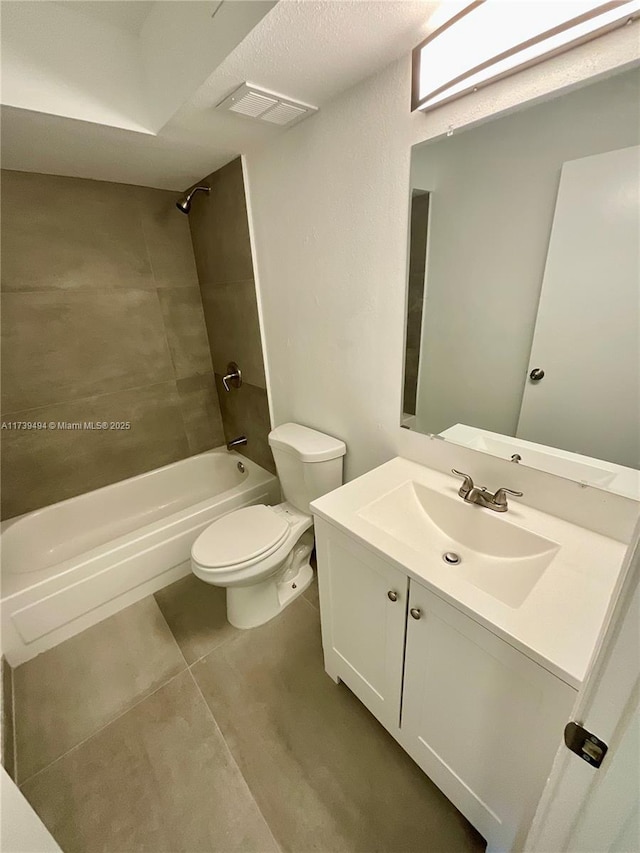 full bathroom featuring vanity, tile patterned flooring, toilet, and tiled shower / bath