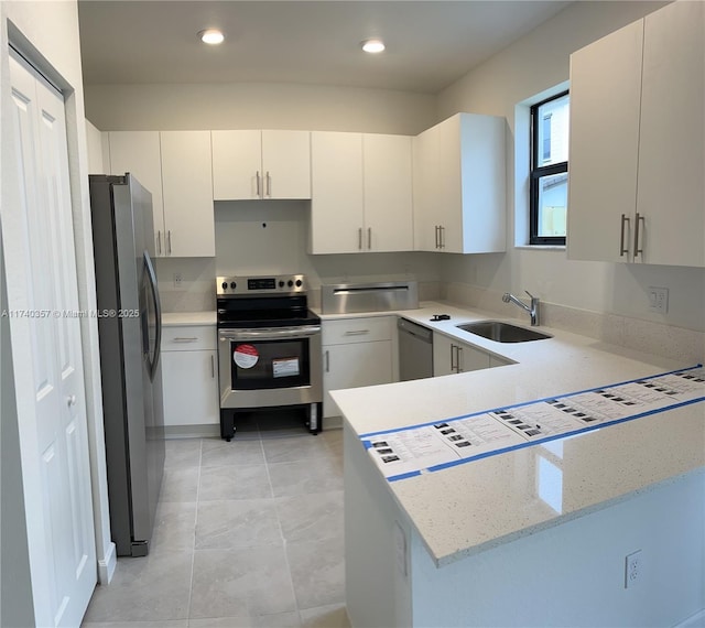 kitchen featuring sink, appliances with stainless steel finishes, light stone countertops, white cabinets, and kitchen peninsula