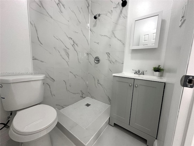 bathroom featuring vanity, tiled shower, and toilet