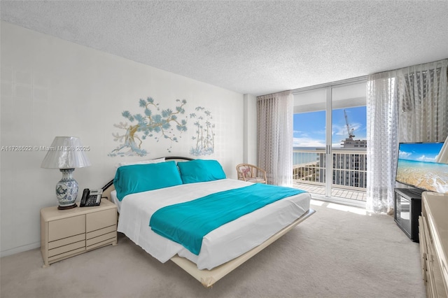 carpeted bedroom with access to outside, a textured ceiling, and a wall of windows