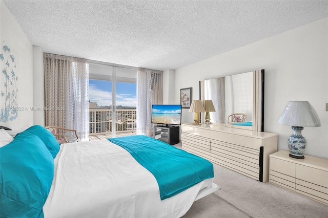 bedroom with light carpet, access to exterior, expansive windows, and a textured ceiling