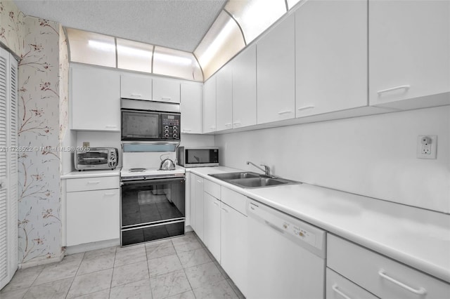 kitchen featuring white dishwasher, electric range oven, white cabinetry, and sink