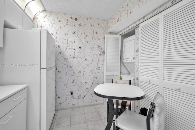 interior space with tile patterned floors, stacked washer / dryer, and a textured ceiling