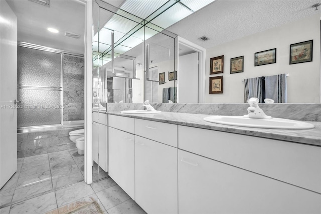 full bathroom with a bidet, bath / shower combo with glass door, vanity, a textured ceiling, and toilet