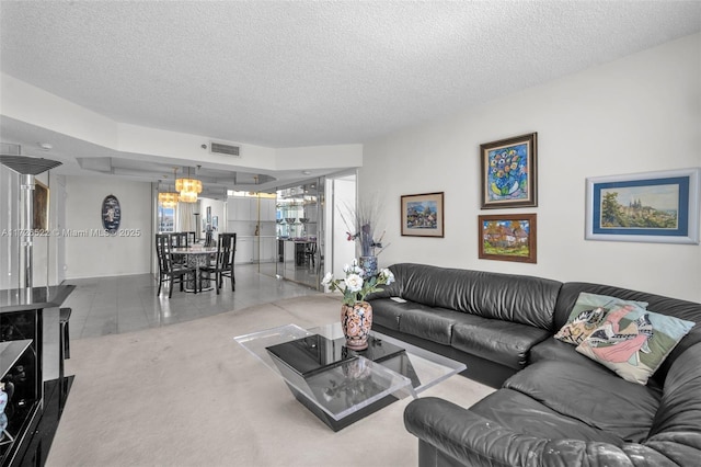 carpeted living room featuring an inviting chandelier and a textured ceiling