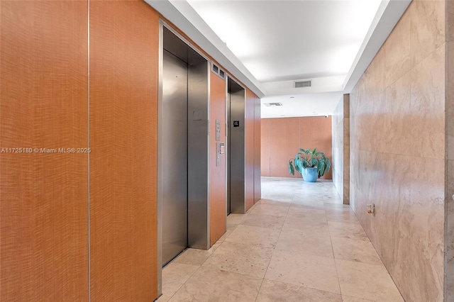 corridor featuring elevator and light tile patterned floors