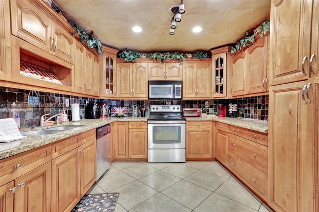 kitchen featuring sink, light tile patterned floors, appliances with stainless steel finishes, backsplash, and light stone countertops