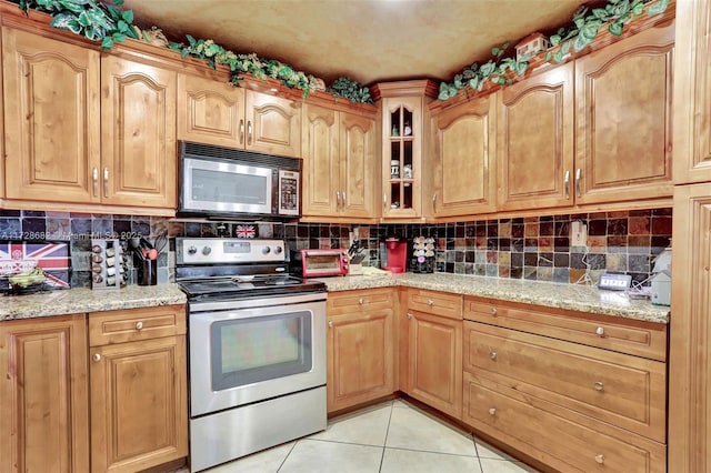 kitchen featuring stainless steel appliances, light tile patterned floors, backsplash, and light stone counters