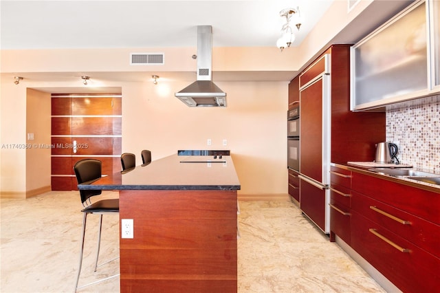 kitchen featuring a kitchen bar, tasteful backsplash, island range hood, black electric cooktop, and paneled fridge