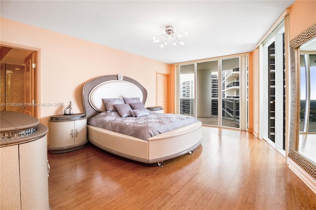 bedroom with multiple windows, hardwood / wood-style floors, floor to ceiling windows, and access to exterior