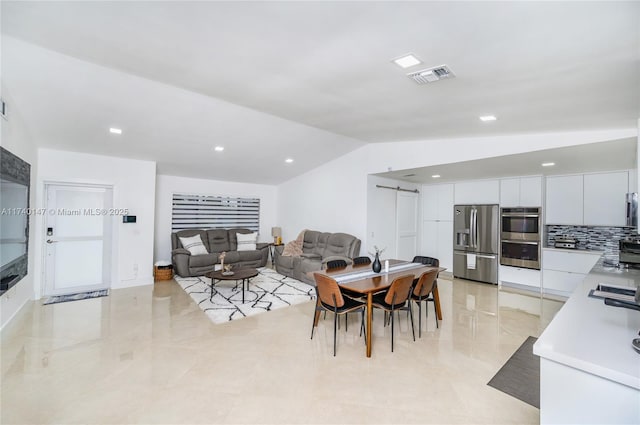 dining area featuring lofted ceiling and a barn door